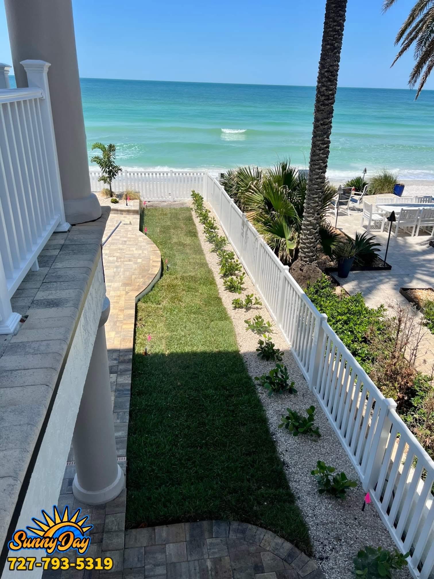 Beachfront residential landscape maintenance with palms, pavers, white fencing, lawn, and coastal planting beds