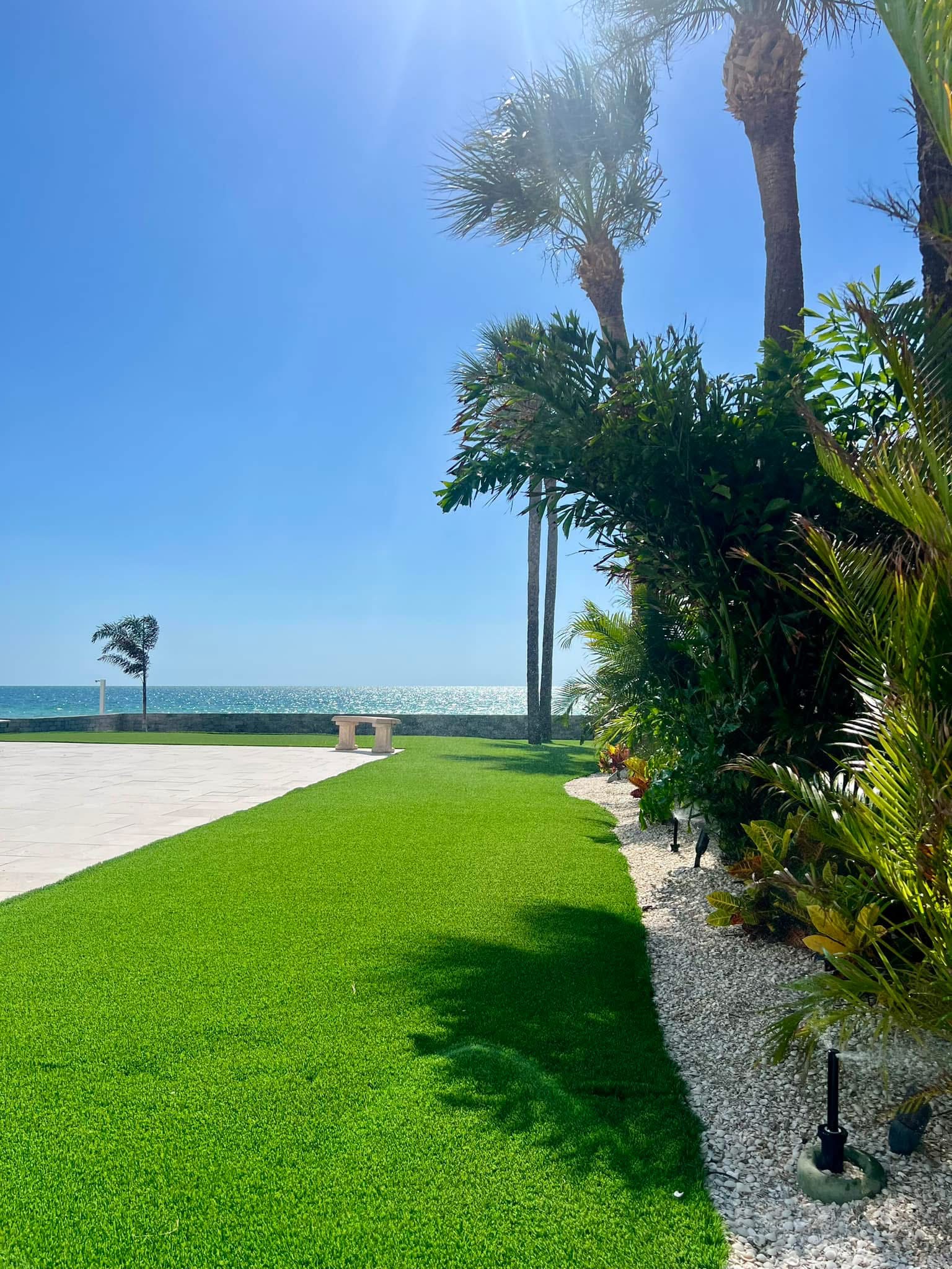 Beachfront turf landscape maintenance with palms, stone beds, coastal lawn, and Gulf views
