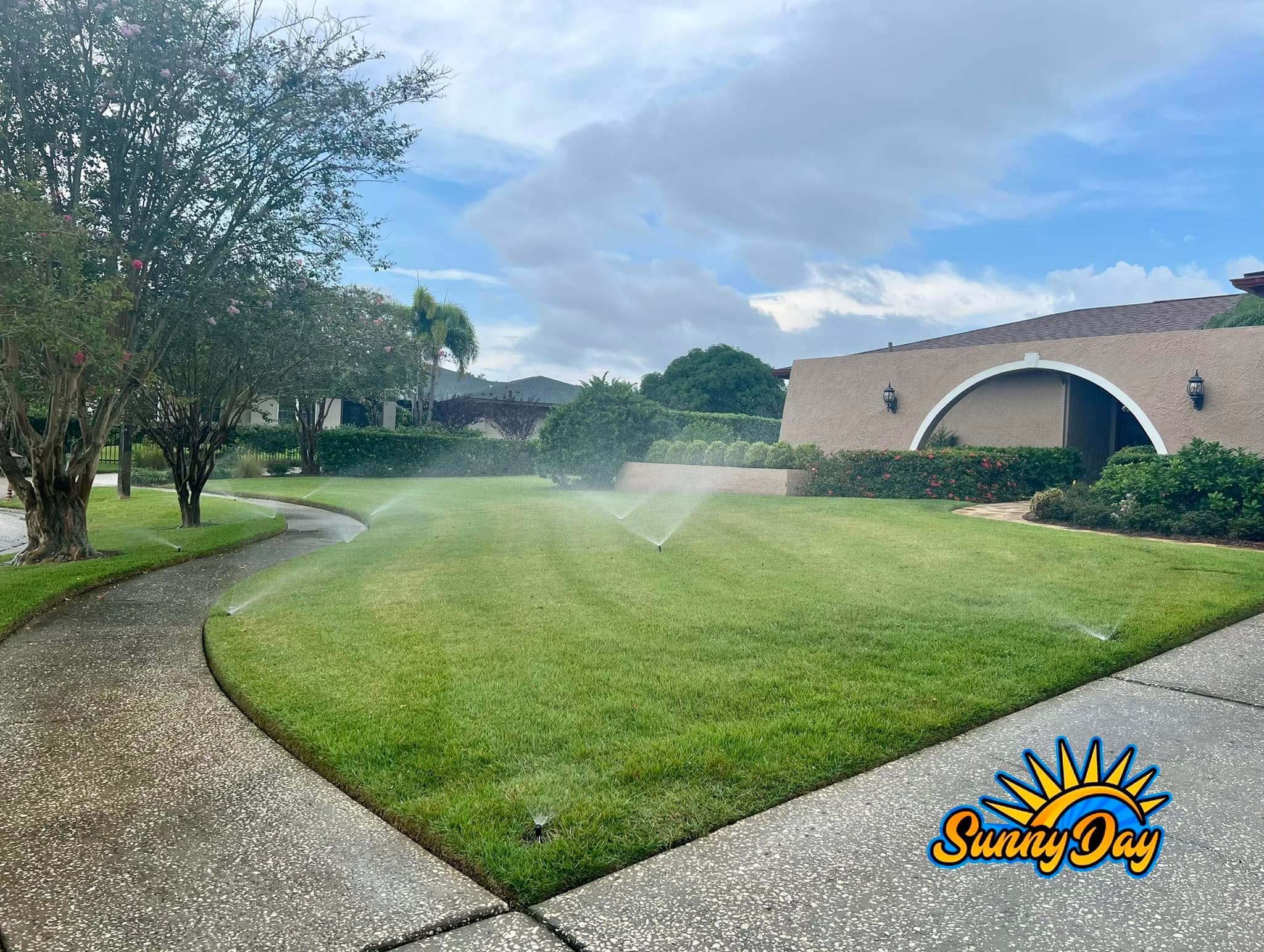 Commercial irrigation sprinkler coverage across a large green lawn and walkway