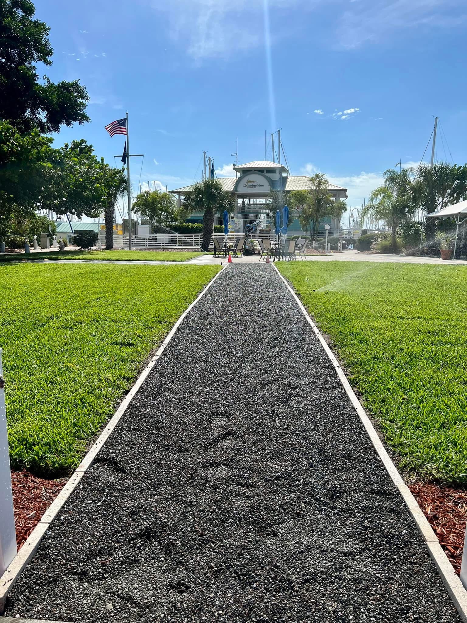 Commercial waterfront walkway with fresh black rock, green lawn, and active irrigation