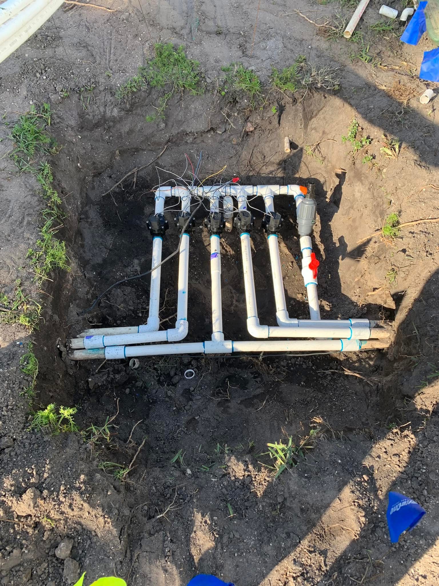 Irrigation system after repair with new PVC manifold, valves, and clean sprinkler piping
